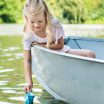 young girl launching paper boat into water
