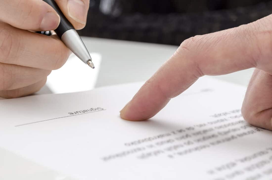 hand holding pen near signature block of contract